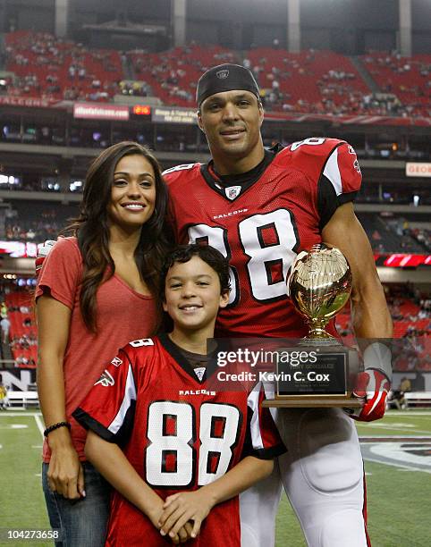 Tony Gonzalez of the Atlanta Falcons poses with his wife October and son Nikko after receiving an award for his 1000th career reception before facing...