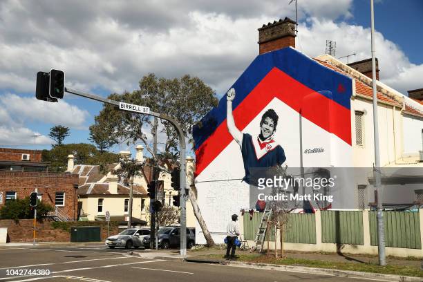 Artist Sid Tapia works on a mural that depicts former Sydney Roosters players Arthur Beetson, Brad Fittler and Anthony Minichiello ahead of the the...