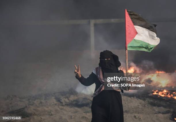 Masked Palestinian woman seen shouting holding a flag during the clashes. 7 Palestinians, including a 14-year-old killed by Israeli fire during a new...