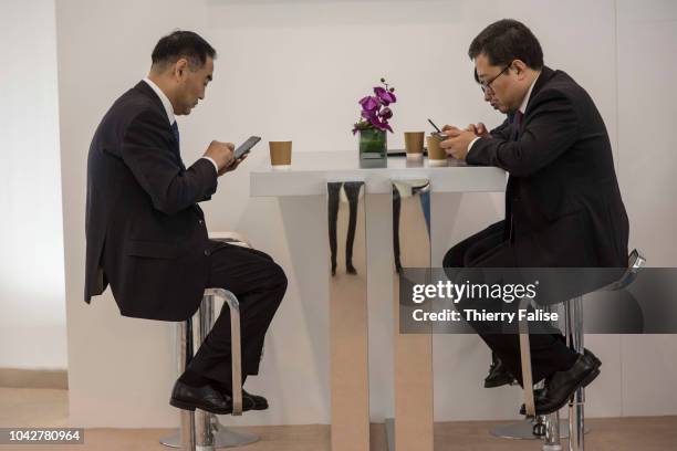 Asian male participants read their mobile phones at a café during the Annual Meeting of the New Champions of the World Economic Forum held in Tianjin...