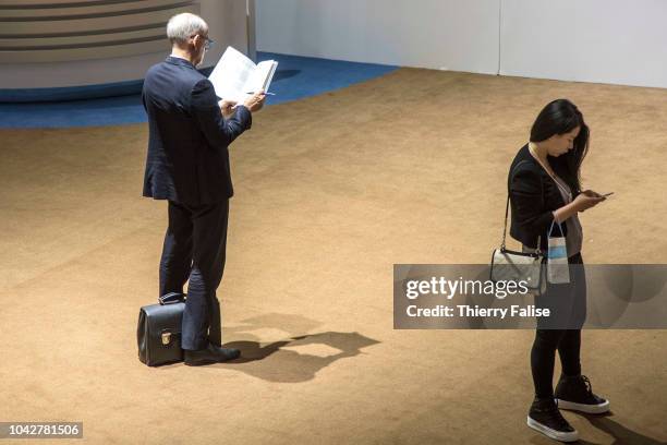 An Asian female participant consults her mobile phone while a Caucasian male reads a report during the Annual Meeting of the New Champions of the...