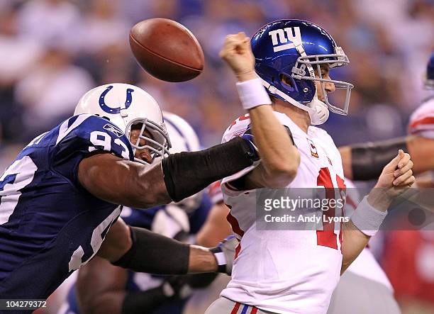 Dwight Freeney of the Indianapolis Colts hits Eli Manning of the New York Giants causing a fumble during the NFL game at Lucas Oil Stadium on...