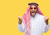 Young handsome man wearing keffiyeh over isolated background celebrating surprised and amazed for success with arms raised and open eyes. Winner concept.