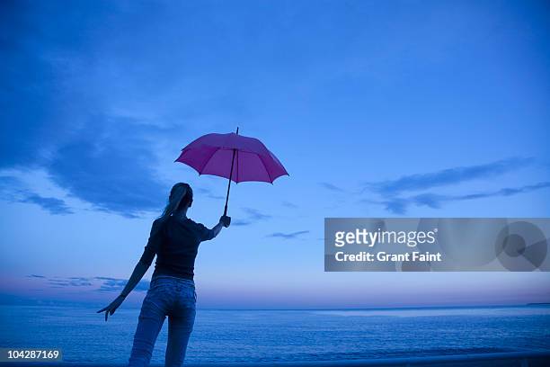 woman holding umbrella near sea. - holding umbrella stock pictures, royalty-free photos & images
