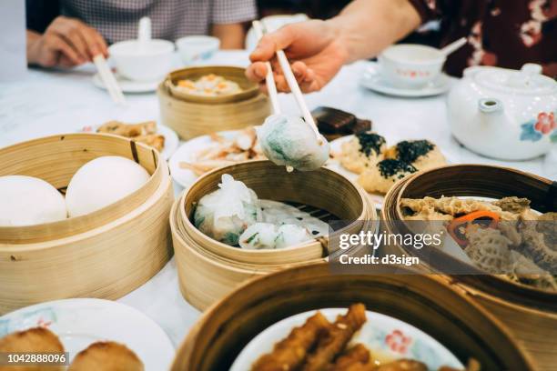 family enjoying family time and having a variety of traditional dim sum in chinese restaurant - chinese restaurant photos et images de collection