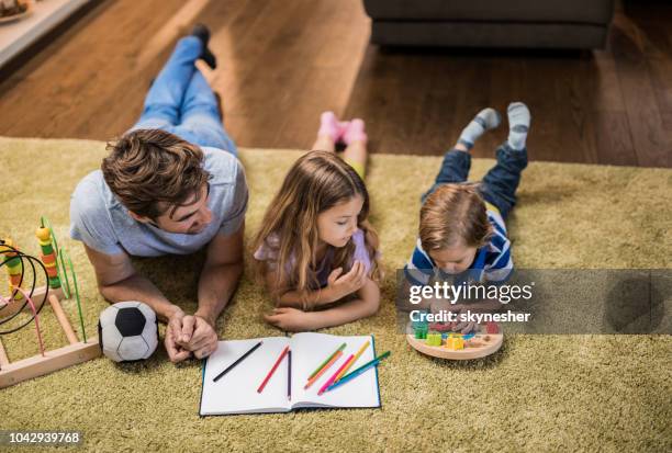 above view of single father spending time with his kids on carpet at home. - family time stock pictures, royalty-free photos & images