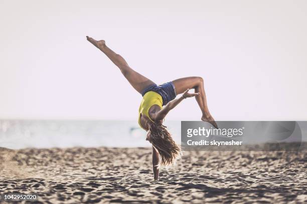 toute la longueur d’une femme faisant le poirier sur le sable à la plage. - handstand beach photos et images de collection