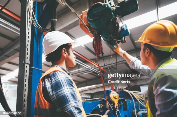 employés de sexe masculin de machines industrielles travaillant avec télécommande pour faire fonctionner la grue - elevator stock photos et images de collection