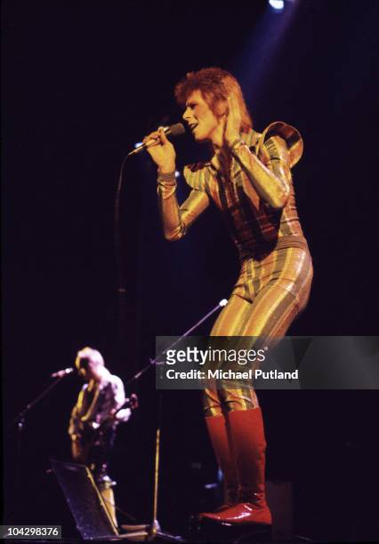 David Bowie performs on stage on his Ziggy Stardust/Aladdin Sane tour, with Mick Ronson in the background, in London, 1973.