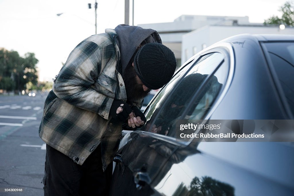 USA, Utah, Salt Lake City, Homeless man breaking into car, side view