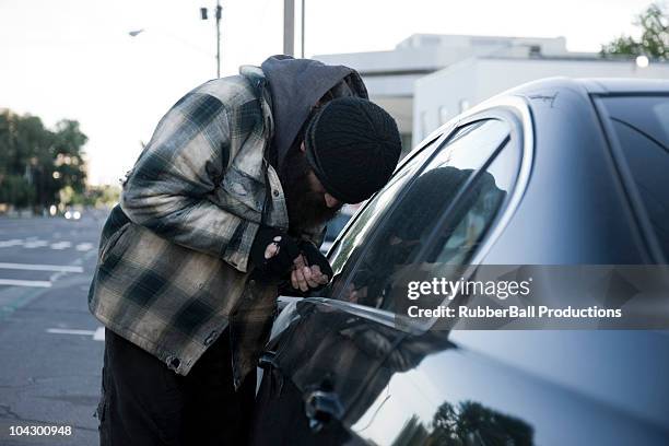 usa, utah, salt lake city, homeless man breaking into car, side view - parte de un vehículo fotografías e imágenes de stock