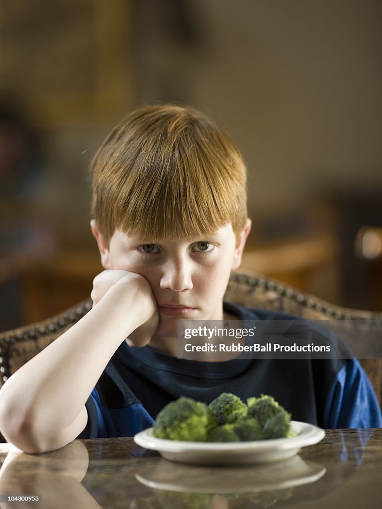 USA, Utah, Portrait of boy (10-11) annoying to eat broccoli