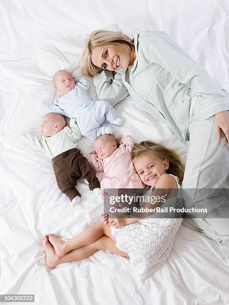 woman lying down with her four children - triplet girls stock pictures, royalty-free photos & images