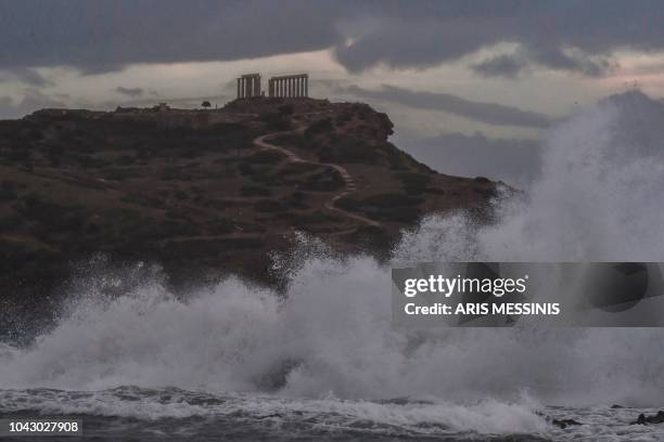 Waves hit the cliffs in front of the ancient Temple of Poseidon at cape Sounion, in southern Athens during bad weather on September 29, 2018.