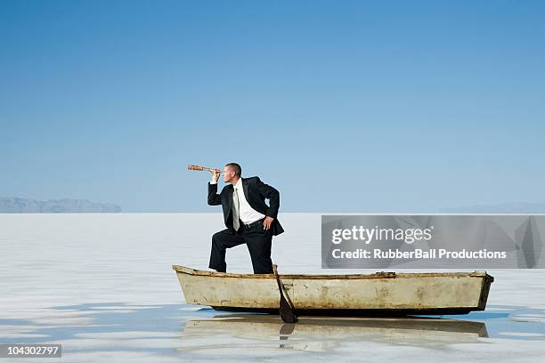 businessman standing in a row boat in the middle of nowhere holding a telescope - day telescope stock pictures, royalty-free photos & images