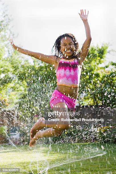 children playing in a sprinkler - jumping sprinkler stock pictures, royalty-free photos & images