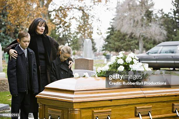 mother and two children at a funeral - mourning parents stock pictures, royalty-free photos & images