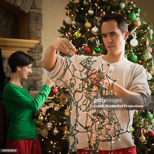 man untangling christmas tree lights - tangled stock pictures, royalty-free photos & images