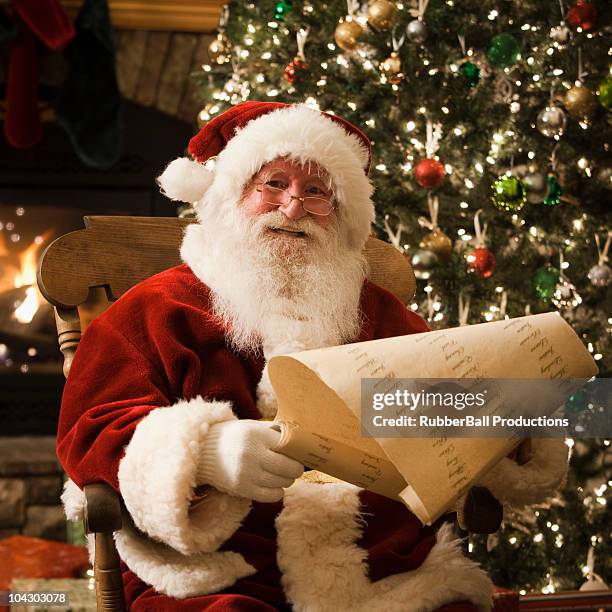 santa claus checking his naughty and nice list - santa clause stockfoto's en -beelden