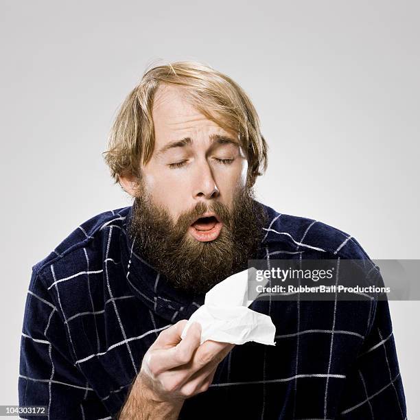 bearded man with a cold wearing a robe - sneezing stockfoto's en -beelden