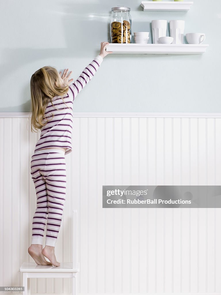 Girl reaching for jar of cookies