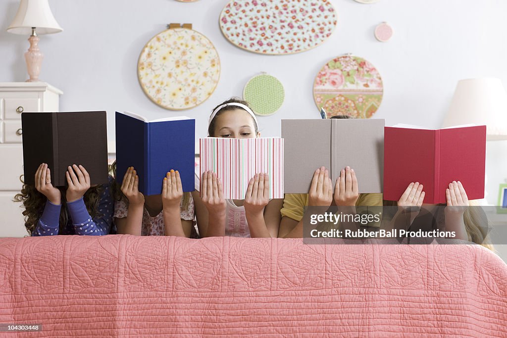 Cinque ragazze su un letto di lettura