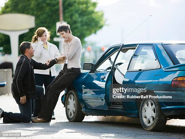 people helping a woman after a car accident - airbag stockfoto's en -beelden