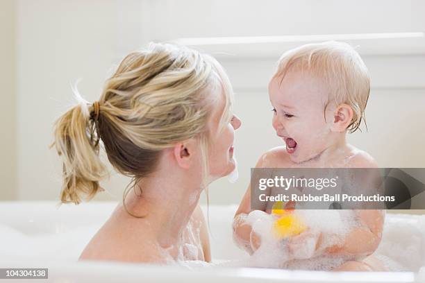 mother and baby taking a bubble bath - woman bath bubbles stock-fotos und bilder