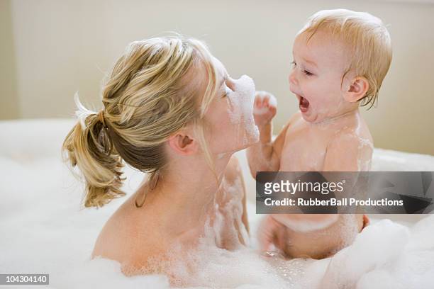 mother and baby taking a bubble bath - mother and baby taking a bath stock-fotos und bilder