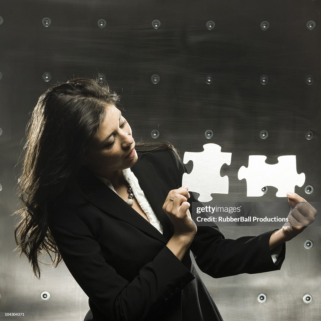 Businesswoman holding two big puzzle pieces