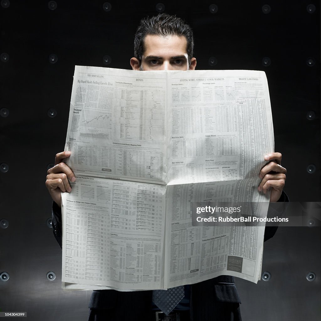 Businessman holding a newspaper and computer