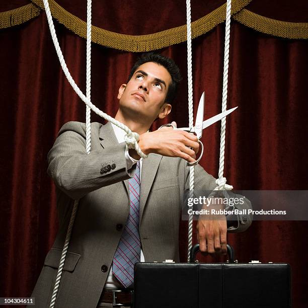 businessman being pulled by strings like a puppet - cutting puppet strings stock pictures, royalty-free photos & images