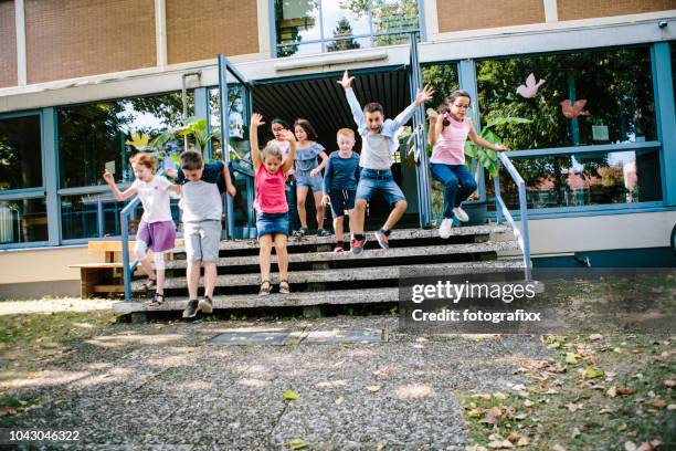 elementary school students run out of school to schoolyard - physical activity children stock pictures, royalty-free photos & images