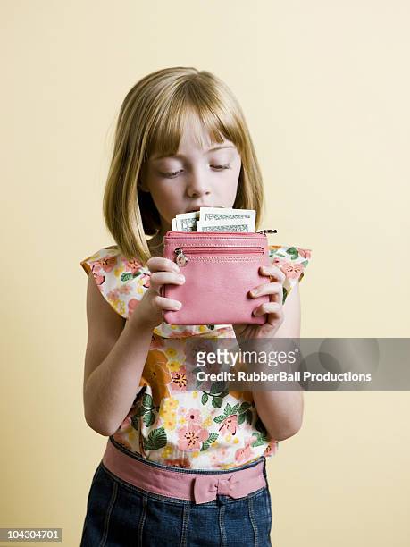 little girl putting money in her pink wallet - brieftasche stock-fotos und bilder