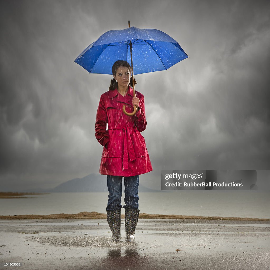 Young woman with umbrella splashing in puddle