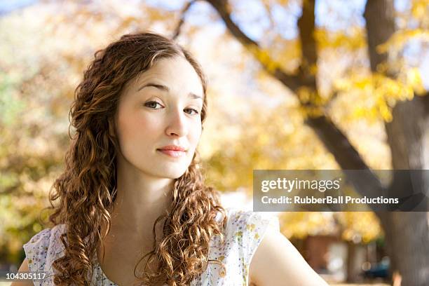portrait of young woman standing in autumn forest - raised eyebrows stockfoto's en -beelden