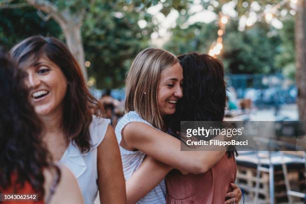 young group of friends meeting up, hugging and greeting each other - local bar stock pictures, royalty-free photos & images