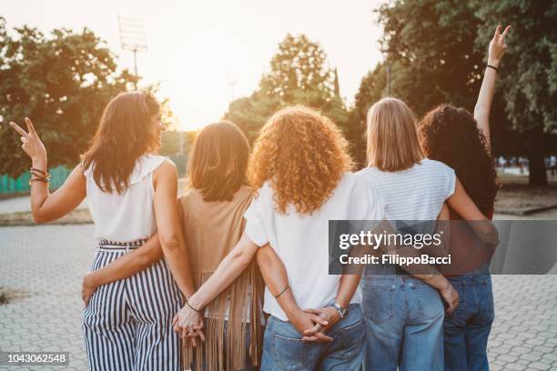 gruppo di amiche che si tengono per mano insieme contro il tramonto - rear view foto e immagini stock