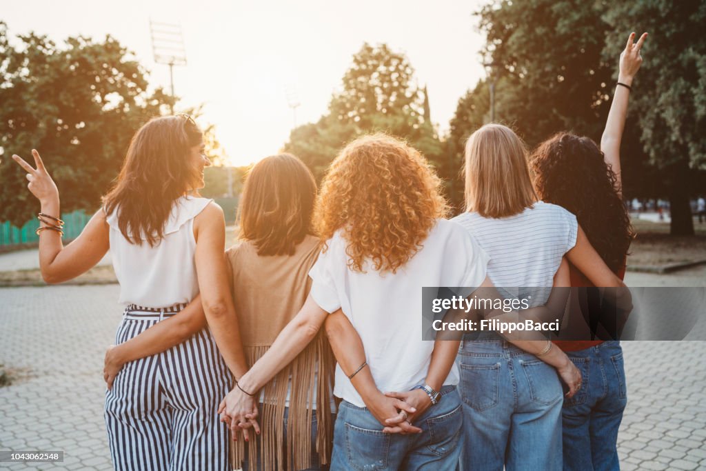 Groep vrouwen vrienden hand in hand samen tegen zonsondergang
