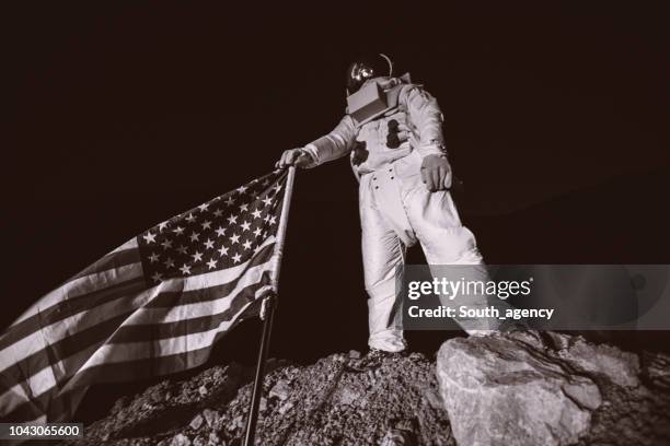 trotse amerikaans astronaut houden van amerikaanse vlag - men costume black and white stockfoto's en -beelden