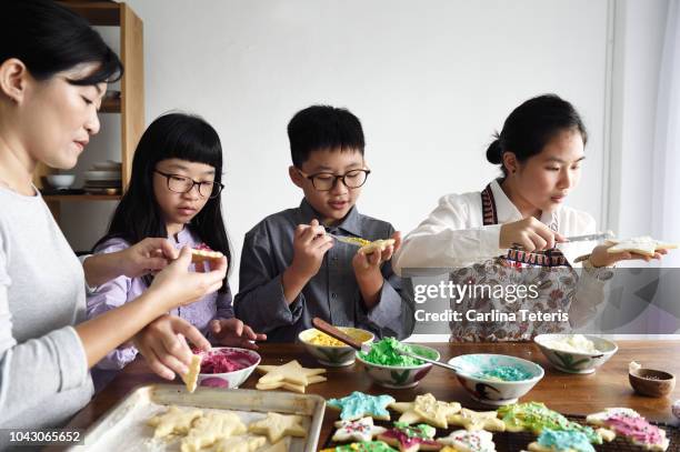 family decorating christmas cookies together - sugar cookie stock pictures, royalty-free photos & images