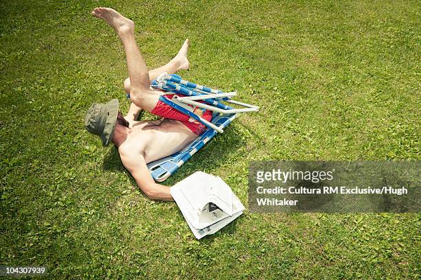 man with newspaper falling off chair - sturz stock-fotos und bilder