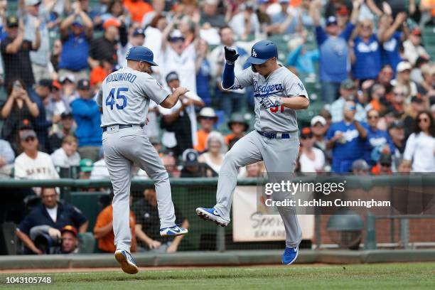 Joc Pederson of the Los Angeles Dodgers celebrates with third base coach Chris Woodward after hitting a lead-off home run in the top of the first...