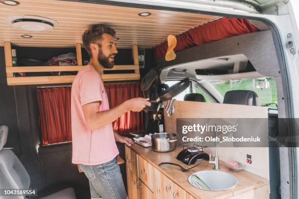 man cooking pancakes  in camper van - indoor camping stock pictures, royalty-free photos & images