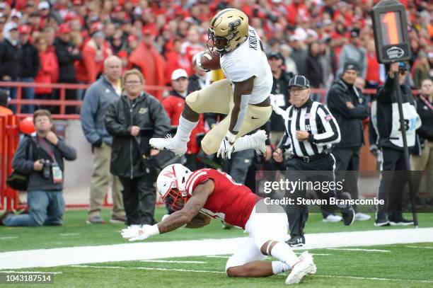 Running back D.J. Knox of the Purdue Boilermakers leaps over the tackle attempt of defensive back Lamar Jackson of the Nebraska Cornhuskers in the...