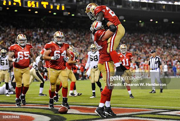 Running back Anthony Dixon of the San Francisco 49ers jumps into the arms of tackle Joe Staley after scoring a touchdown against the New Orleans...