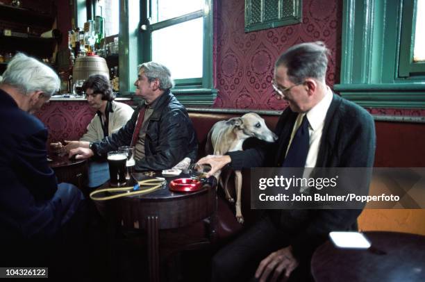 Man pours beer into an ashtray for his dog at a pub in Manchester, England in 1976.