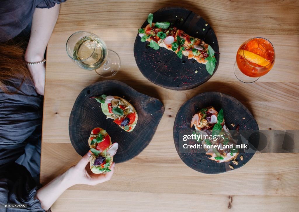 Woman eating appetizers with a glass of white wine and Spritz
