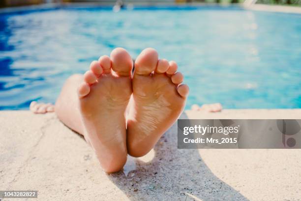 boy lying in a swimming pool with his legs over the edge - sola-do-pé imagens e fotografias de stock