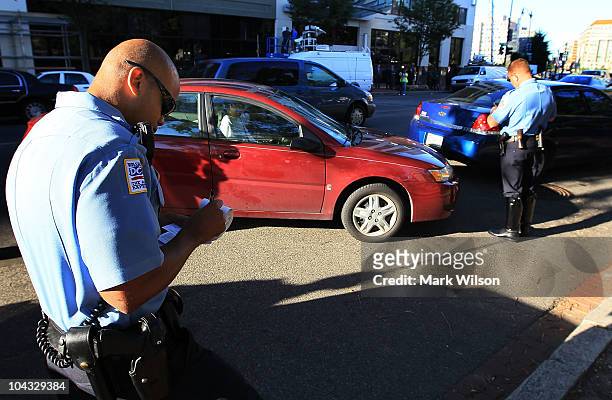 Metropolitan Police Officer Tyrone Gross and Officer J.D. Hansohn write warning tickets to motorists who were talking on their cell phones on...